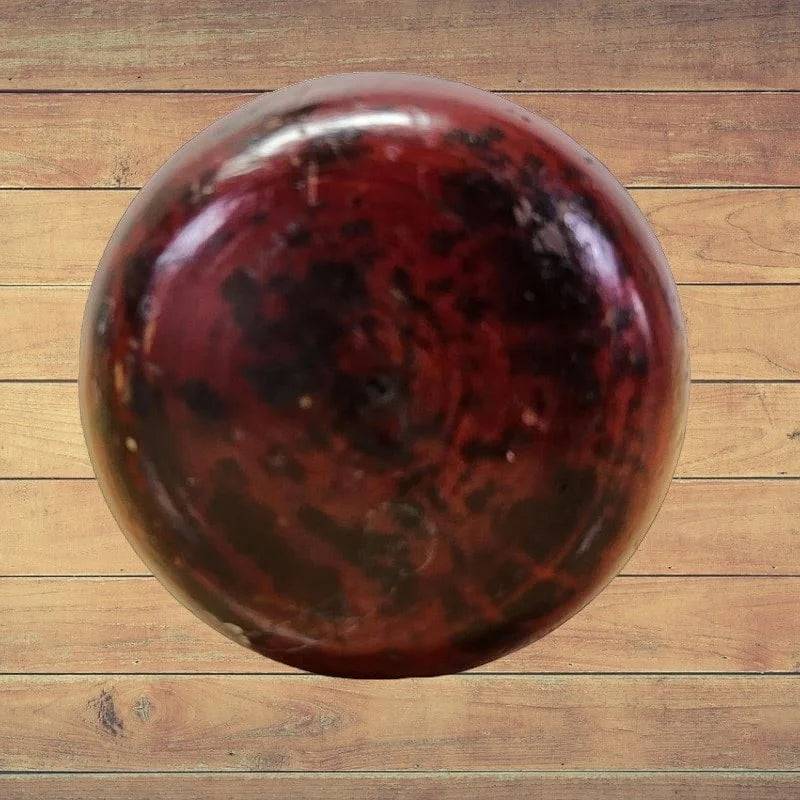 A wooden floor with an antique drill and handle made of wood lying on it.