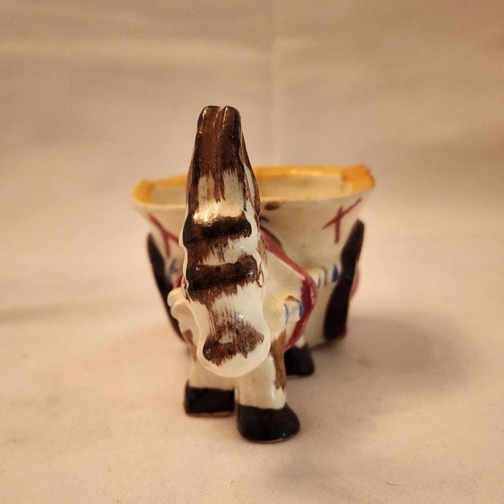 A ceramic donkey with a wheelbarrow, showcasing a whimsical and charming display of craftsmanship.