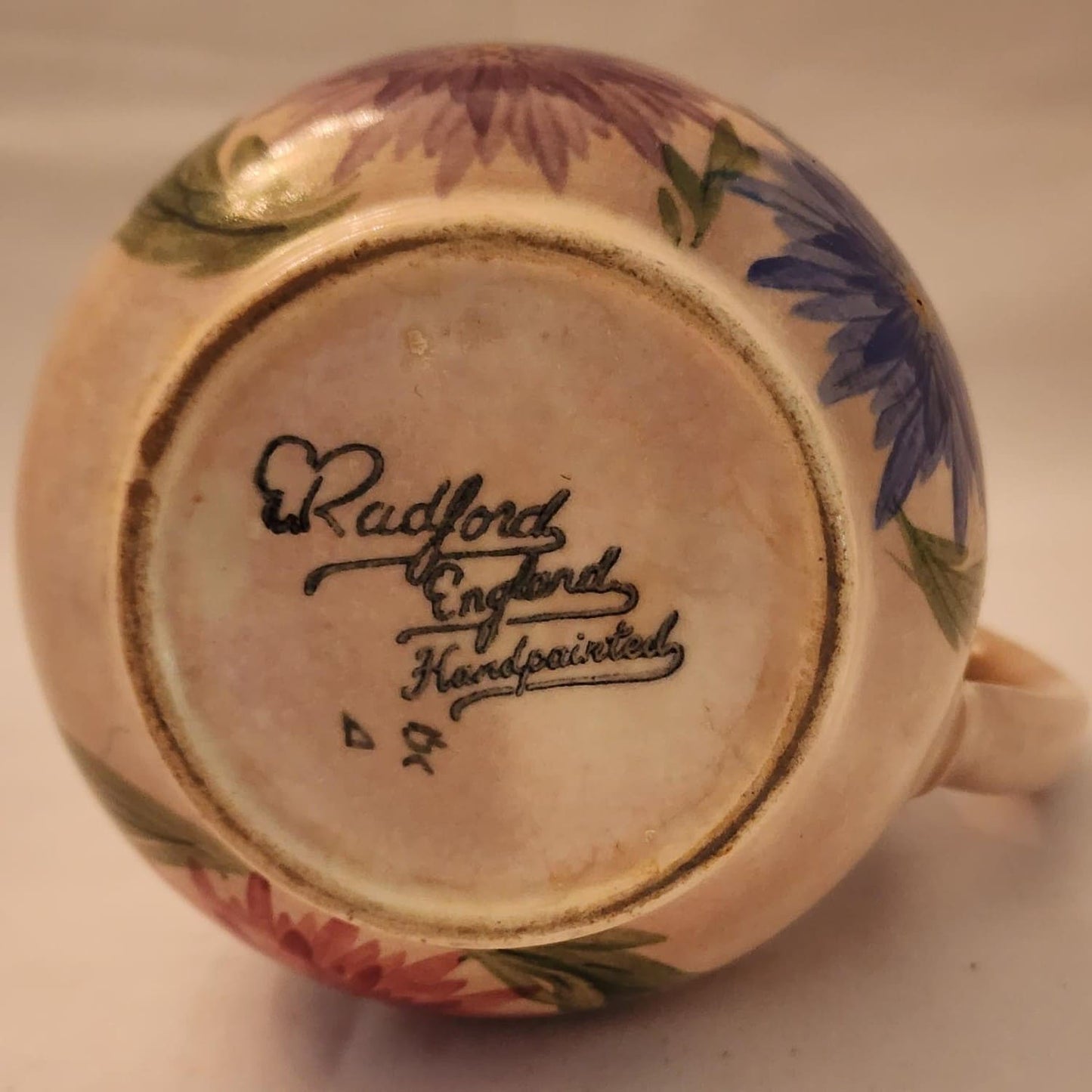 A pitcher featuring a beautiful floral design, hand-painted for a charming touch.