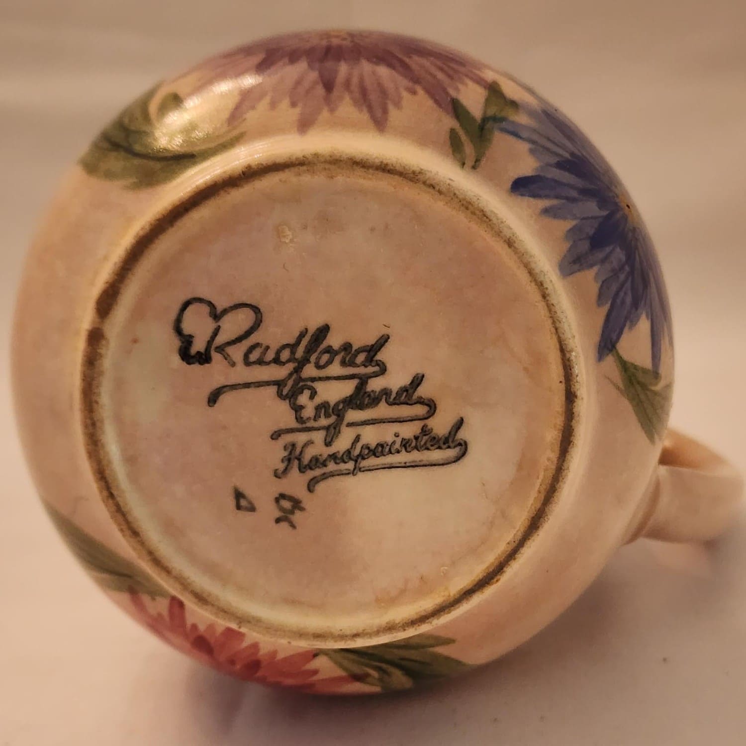 A pitcher featuring a beautiful floral design, hand-painted for a charming touch.