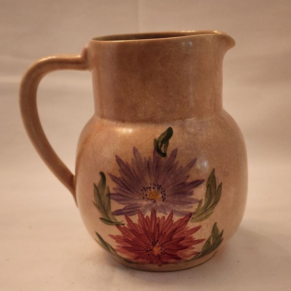 A pitcher featuring a beautiful floral design, hand-painted for a charming touch.