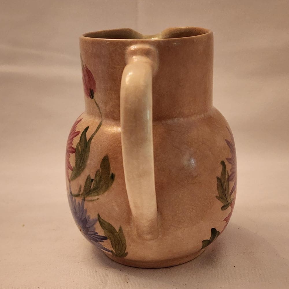A pitcher featuring a beautiful floral design, hand-painted for a charming touch.