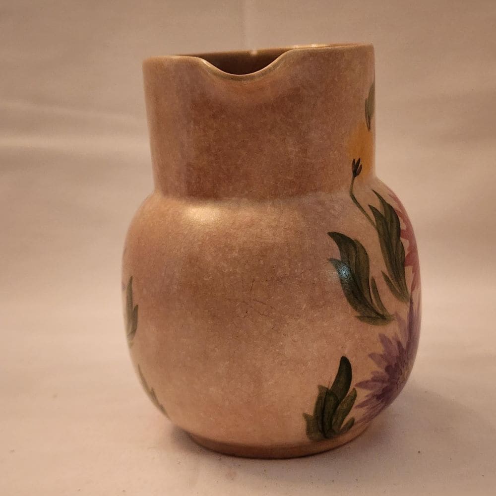 A pitcher featuring a beautiful floral design, hand-painted for a charming touch.