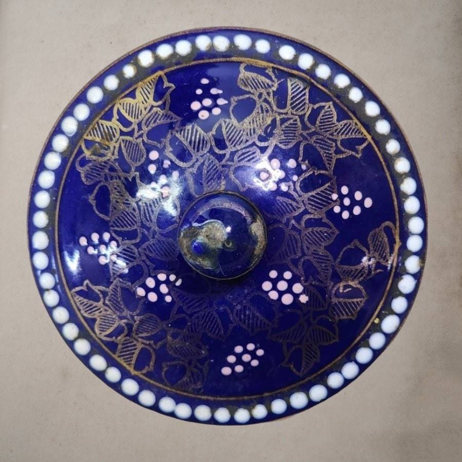 A blue teapot with gold flowers and images all over.