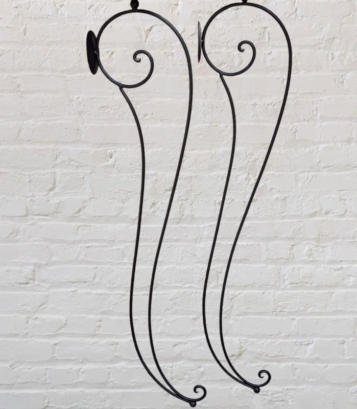 A black iron candle holder with two lit candles on top.