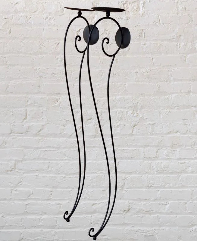 A black iron candle holder with two lit candles on top.