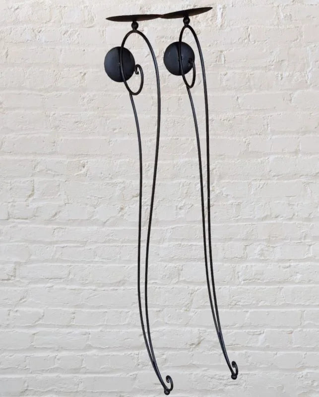 A black iron candle holder with two lit candles on top.