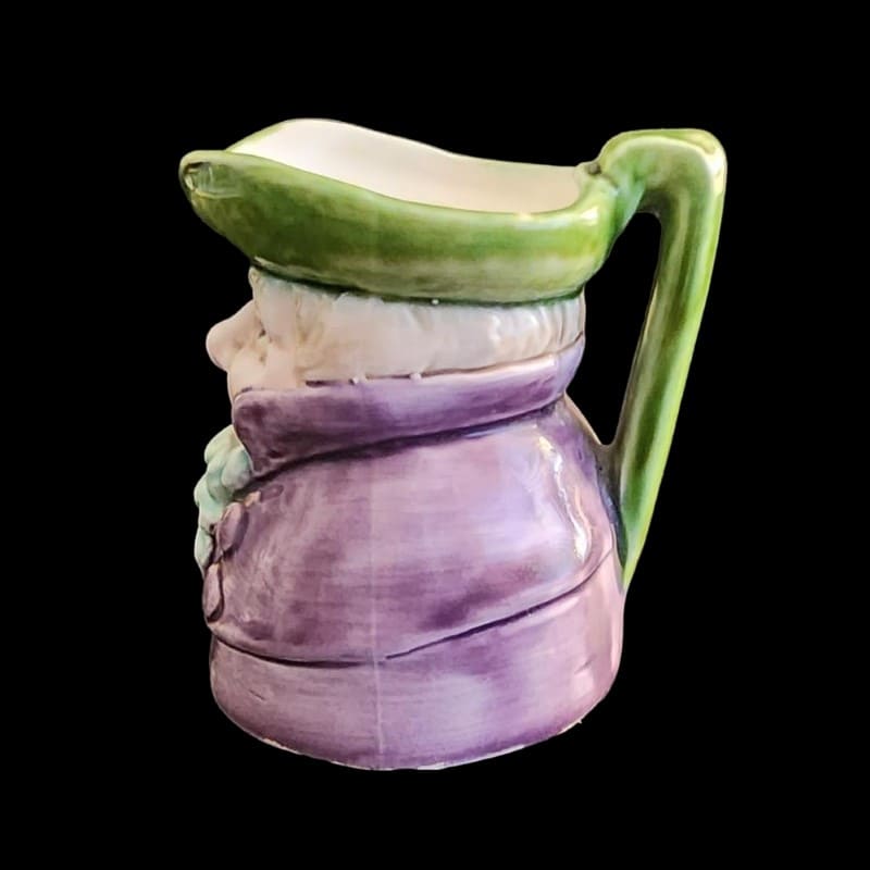 A small porcelain figurine wearing a green hat and a purple coat, showcasing intricate craftsmanship.