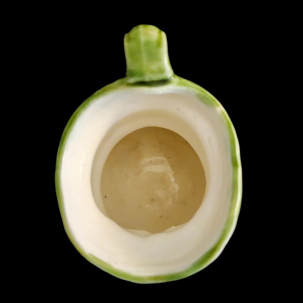 A small porcelain figurine wearing a green hat and a purple coat, showcasing intricate craftsmanship.