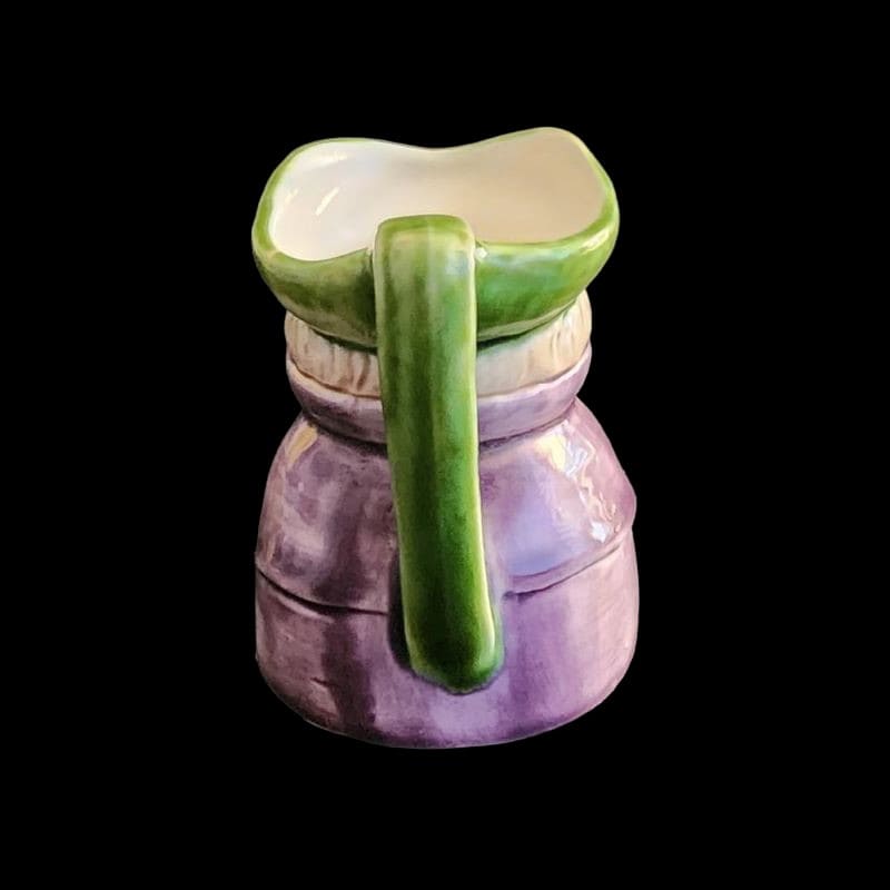 A small porcelain figurine wearing a green hat and a purple coat, showcasing intricate craftsmanship.