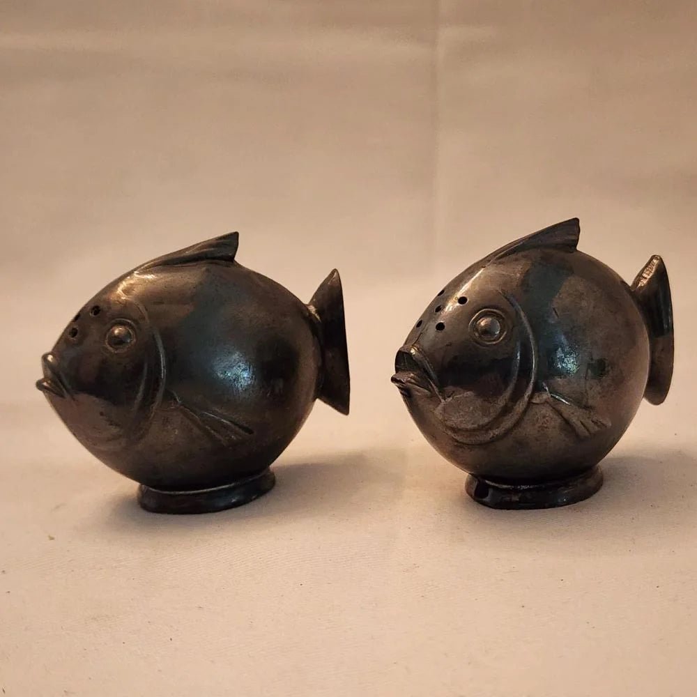 Pair of black fish salt and pepper shakers on a white surface.