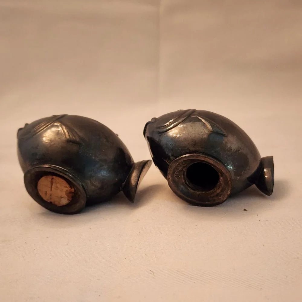 Pair of black fish salt and pepper shakers on a white surface.
