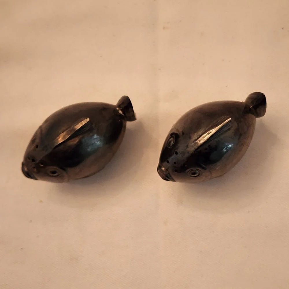 Pair of black fish salt and pepper shakers on a white surface.