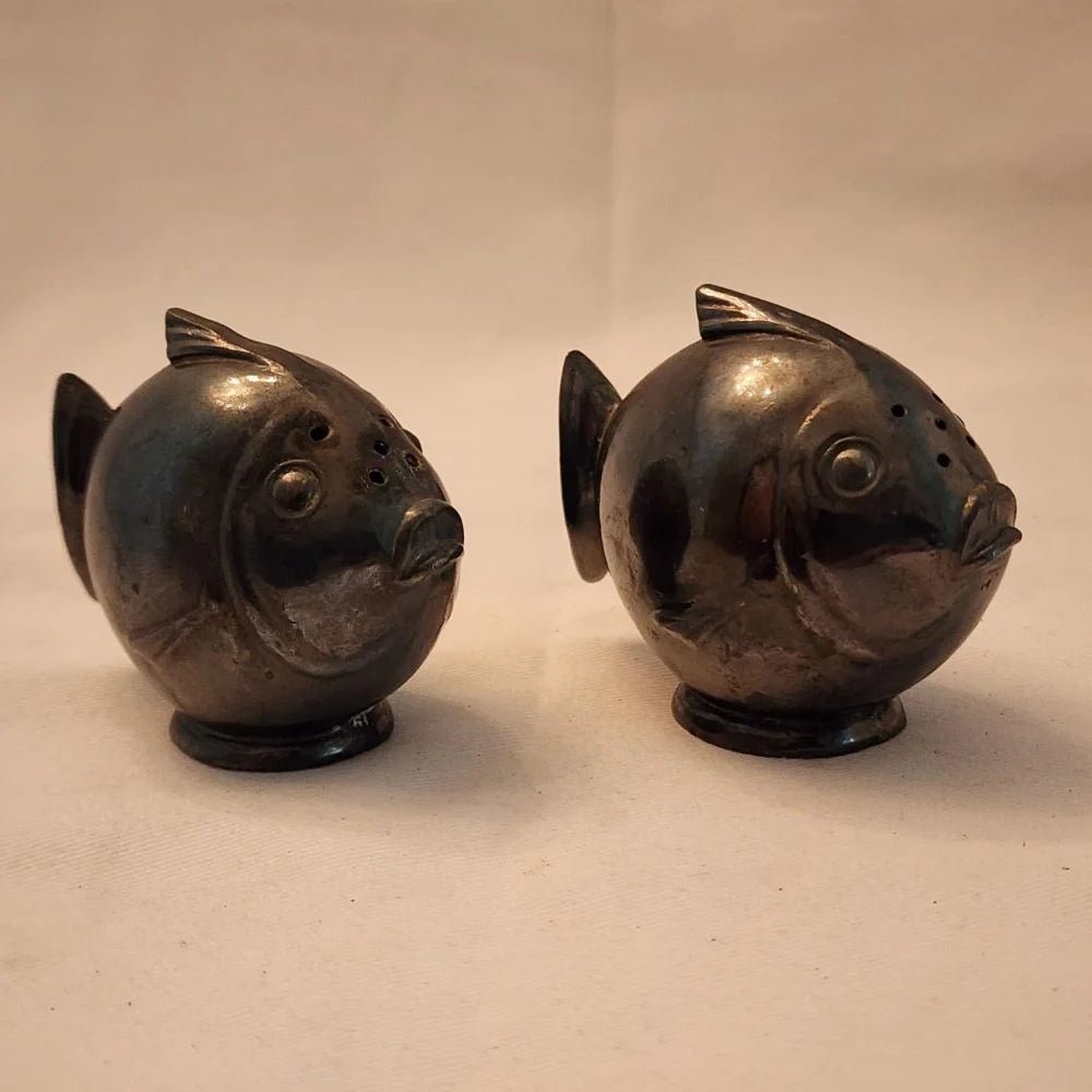 Pair of black fish salt and pepper shakers on a white surface.