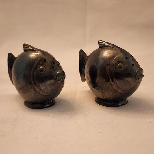 Pair of black fish salt and pepper shakers on a white surface.