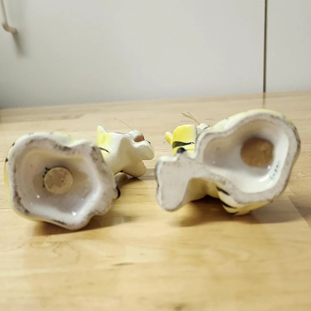 Two ceramic tiger salt and pepper shakers sitting on a table, showcasing intricate details and a lifelike appearance.