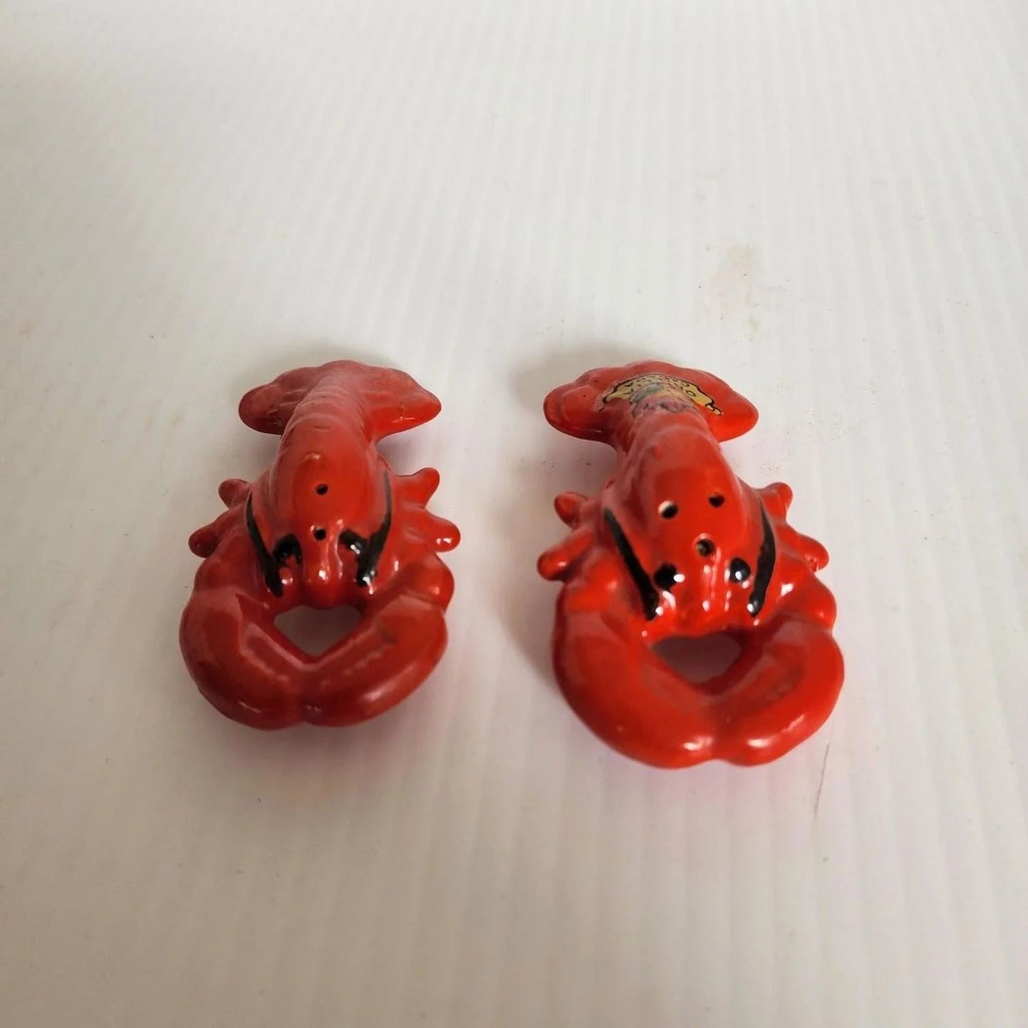 Two lobster-shaped salt and pepper shakers, perfect for adding flavor to your meals.