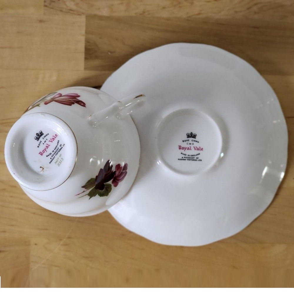 A teacup with dark red roses placed on top of books.