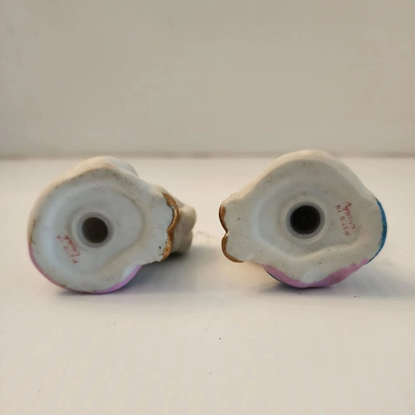 Two ceramic unicorn figurines sitting on a table, one white and one pink, with intricate details and a glossy finish.