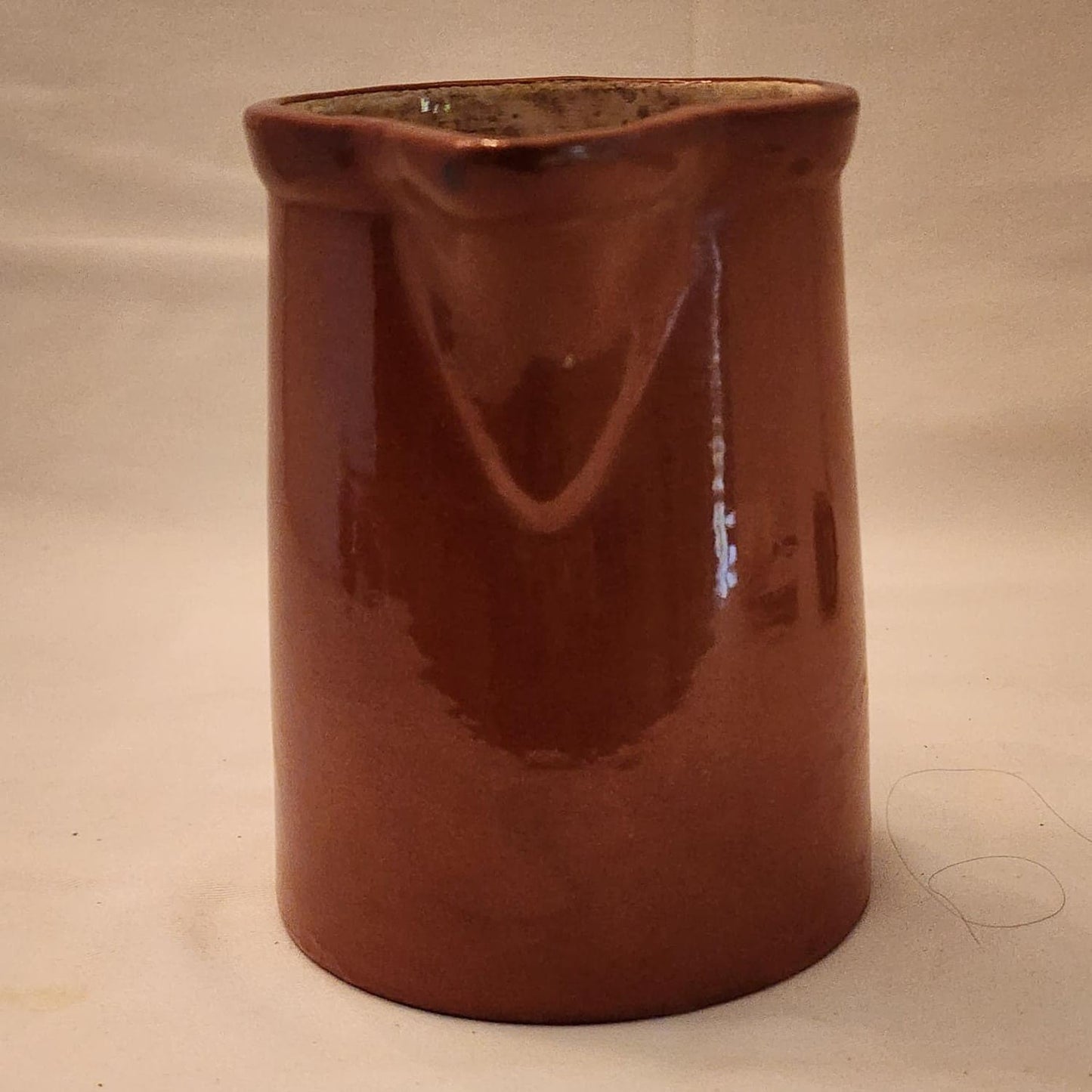 A brown jug with a handle on a white background.