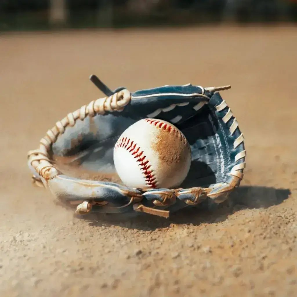 A baseball and glove on a baseball field, ready for a game.