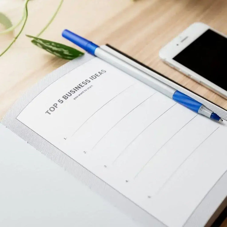 A pad of paper with things to do and pens beside it planning for the business.