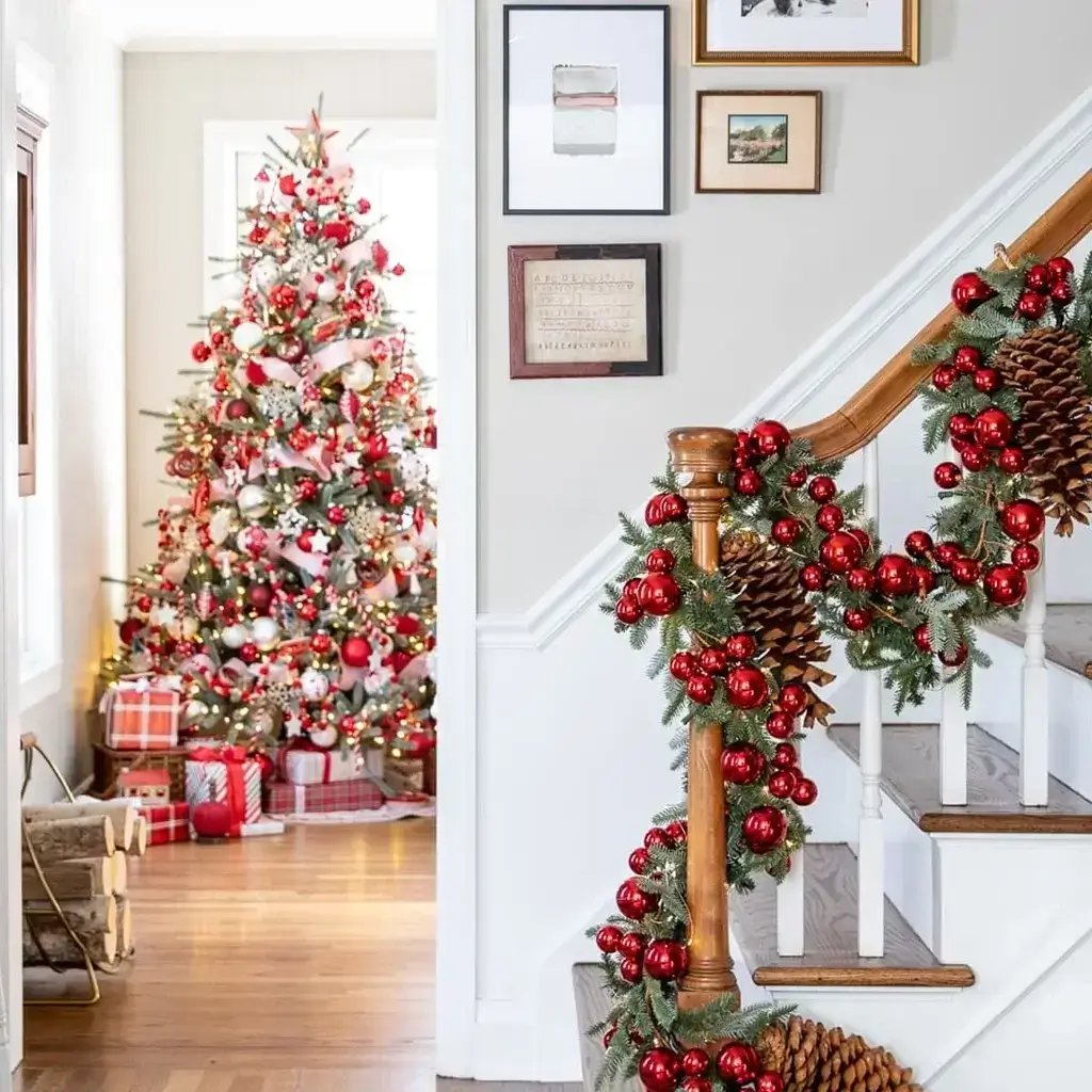 A festive staircase adorned with red and white Christmas decorations with a fully decorated Christmas tree in the background