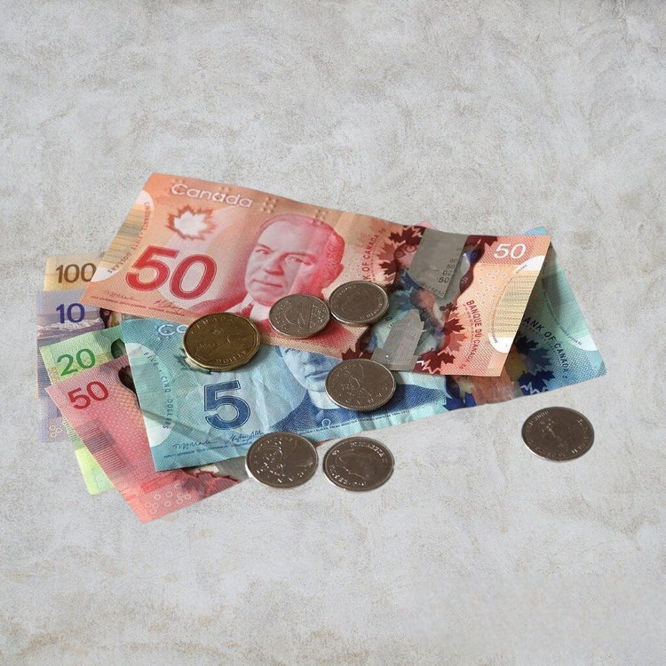 Various denominations of Canadian currency and coins displayed on a table, showcasing their distinct designs.