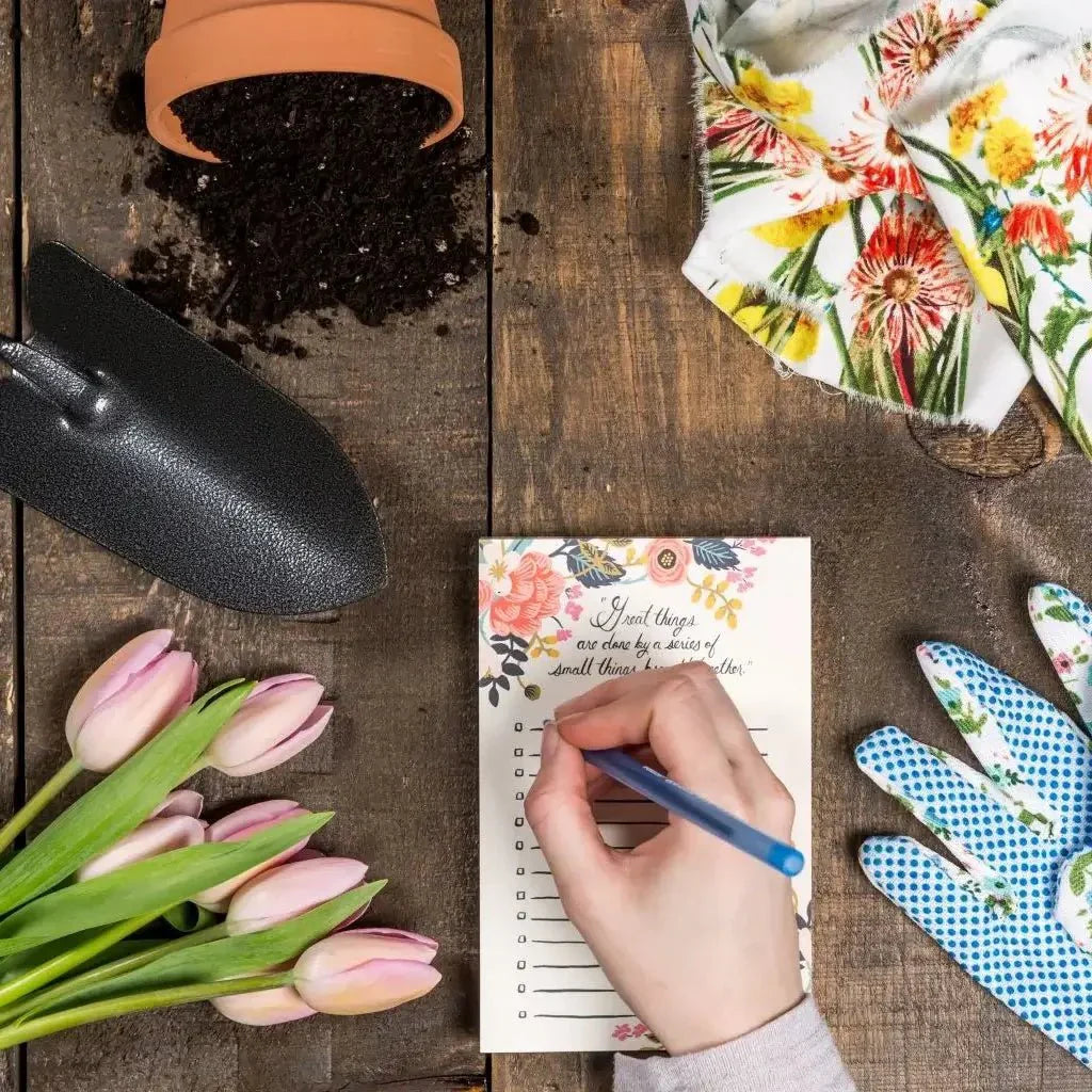 Gardening tools and a woman's hand writing in a notebook.