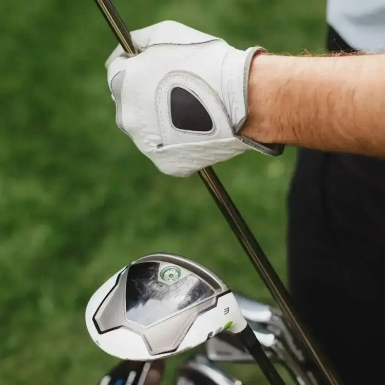 A person holding a golf club and a driver, ready to tee off on a golf course ready to think about trading golf cards