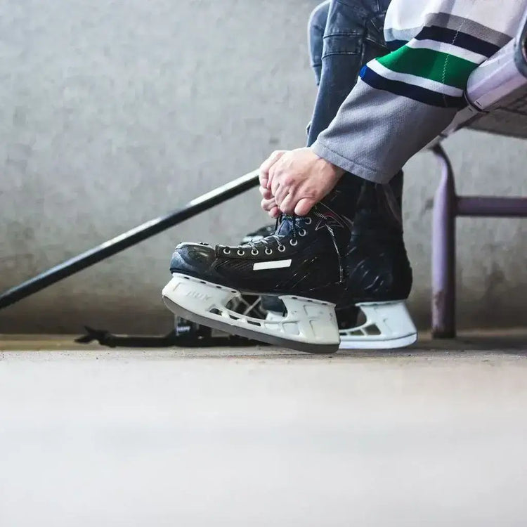 A person tying on their hockey skates, surrounded by Hockey Cards and Coins of legendary hockey players.