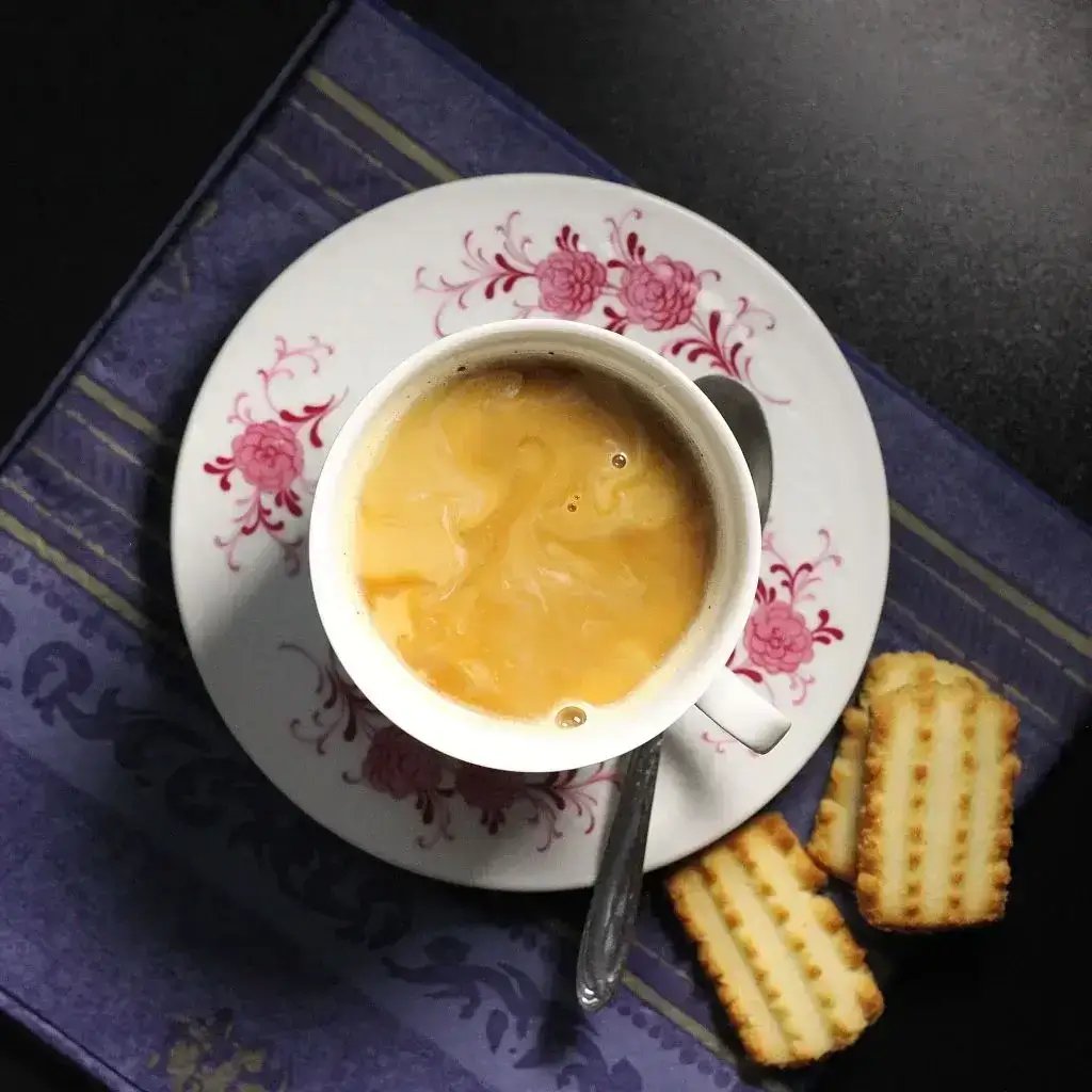 A cup of coffee and cookies on a saucer, perfect for a cozy afternoon treat.