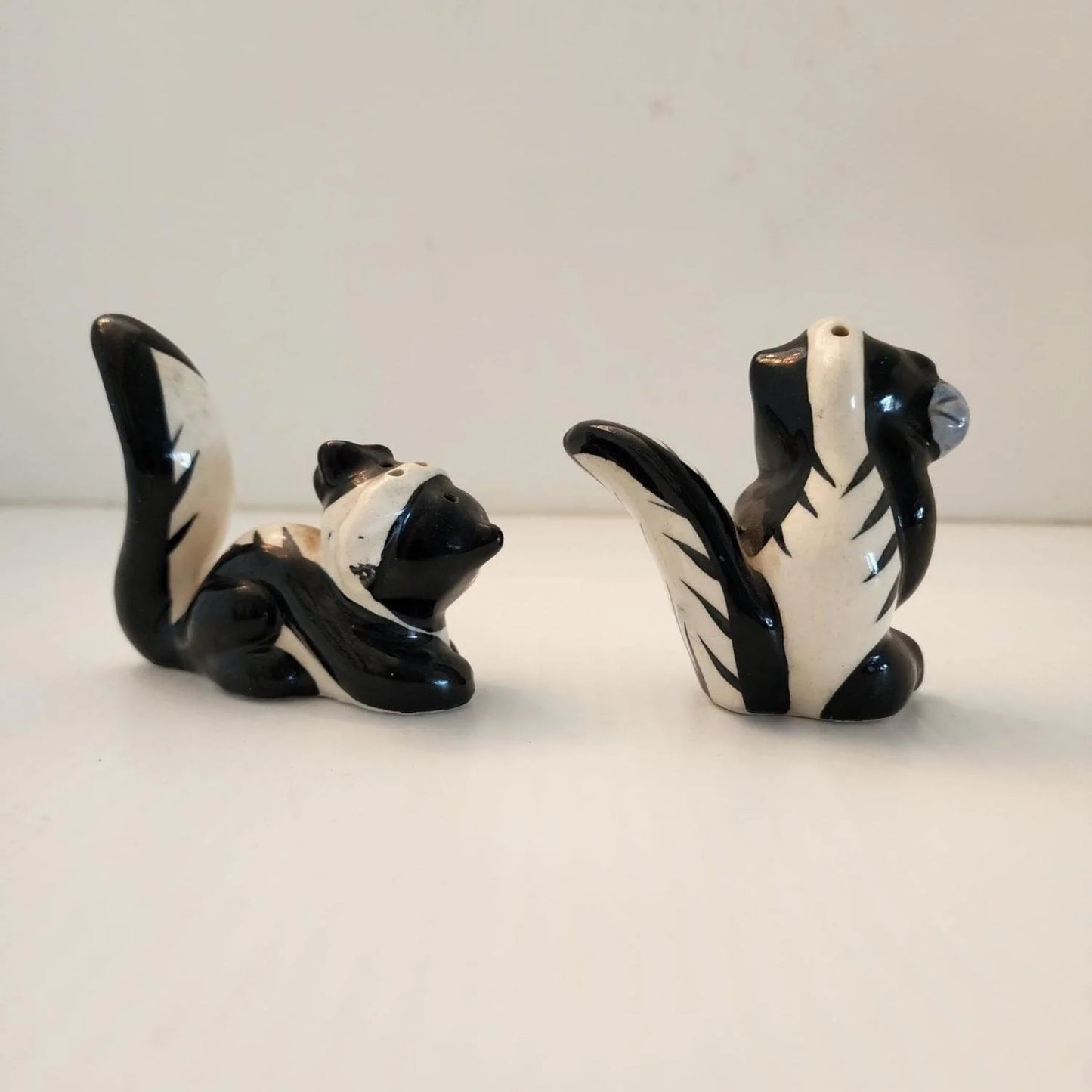 Two ceramic skunks, one black and one white, sitting on a table.