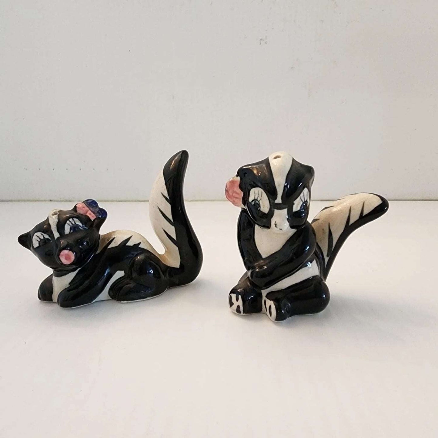 Two ceramic skunks, one black and one white, sitting on a table.