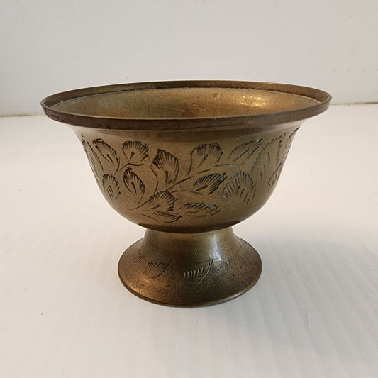 A brass bowl with an intricate design etched on its surface.