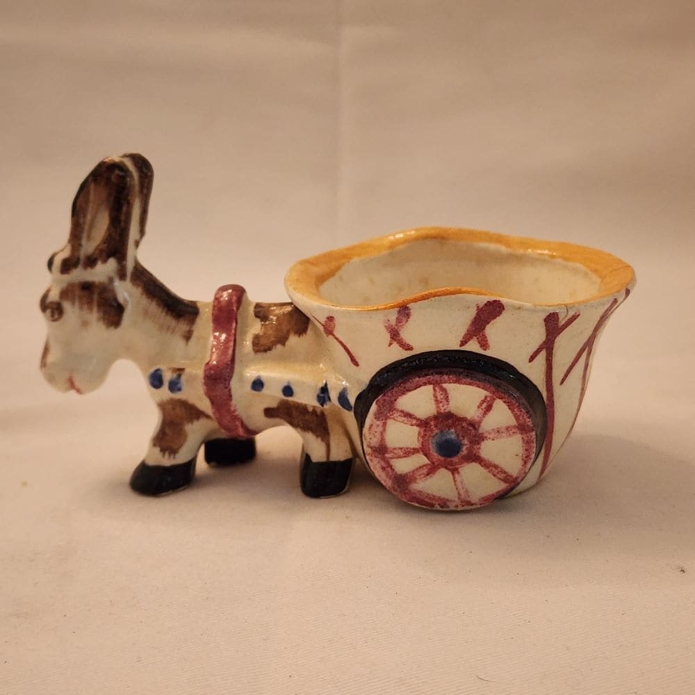 A ceramic donkey with a wheelbarrow, showcasing a whimsical and charming display of craftsmanship.