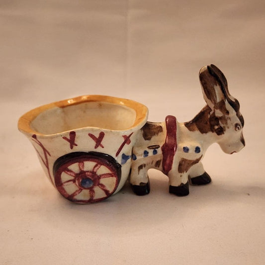 A ceramic donkey with a wheelbarrow, showcasing a whimsical and charming display of craftsmanship.