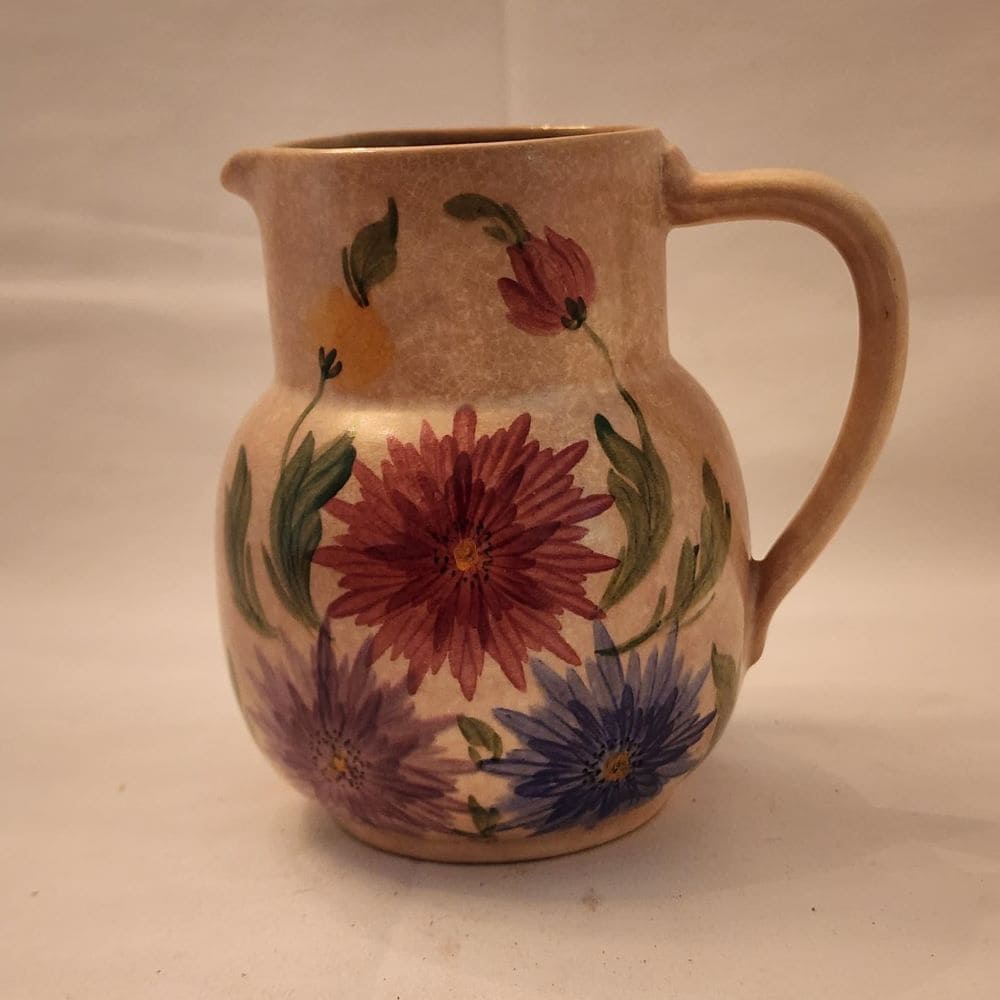 A pitcher featuring a beautiful floral design, hand-painted for a charming touch.