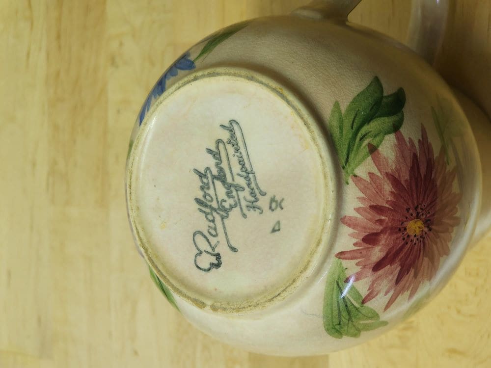 A pitcher featuring a beautiful floral design, hand-painted for a charming touch.