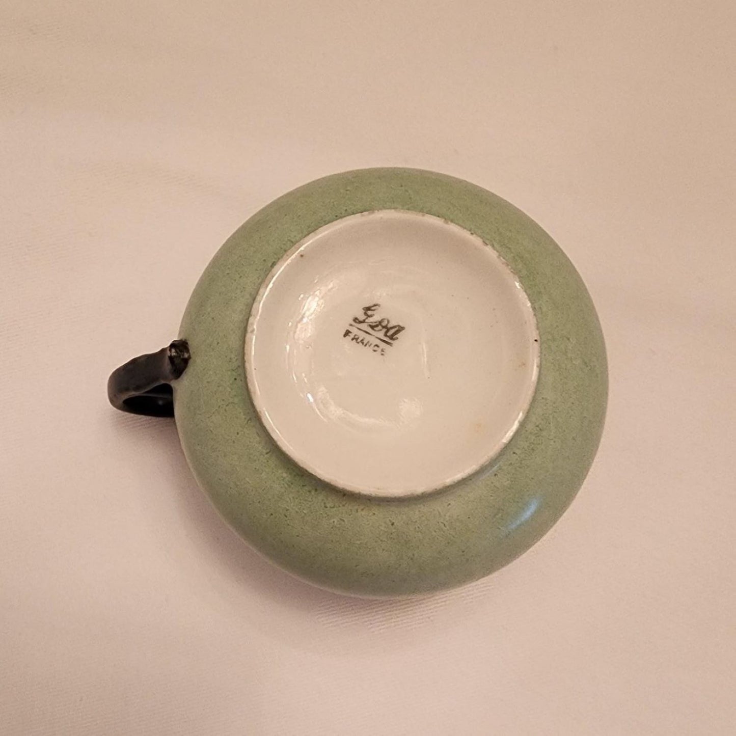 Green cup and saucer with bird design, perfect for enjoying a morning coffee in the garden.