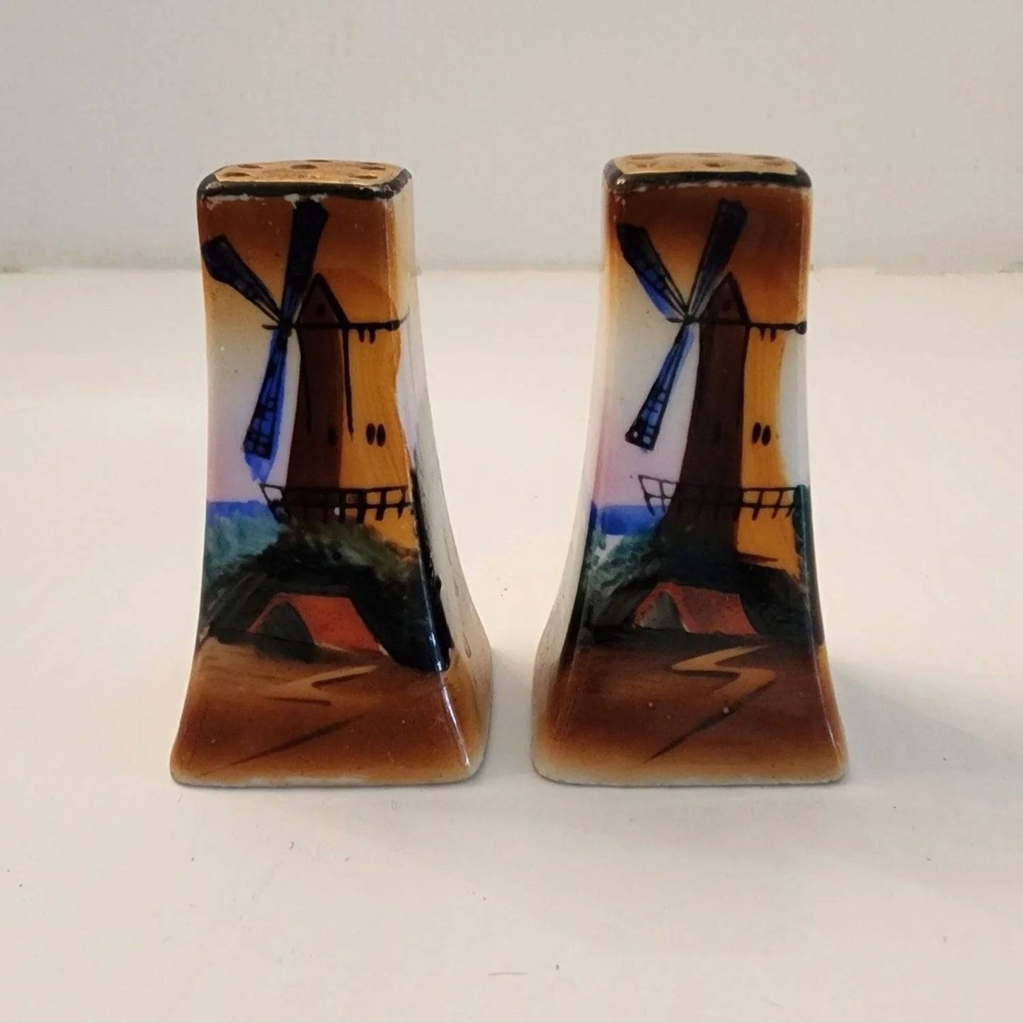 Two small salt and pepper shakers featuring a windmill design. Perfect for adding flavor to your meals.