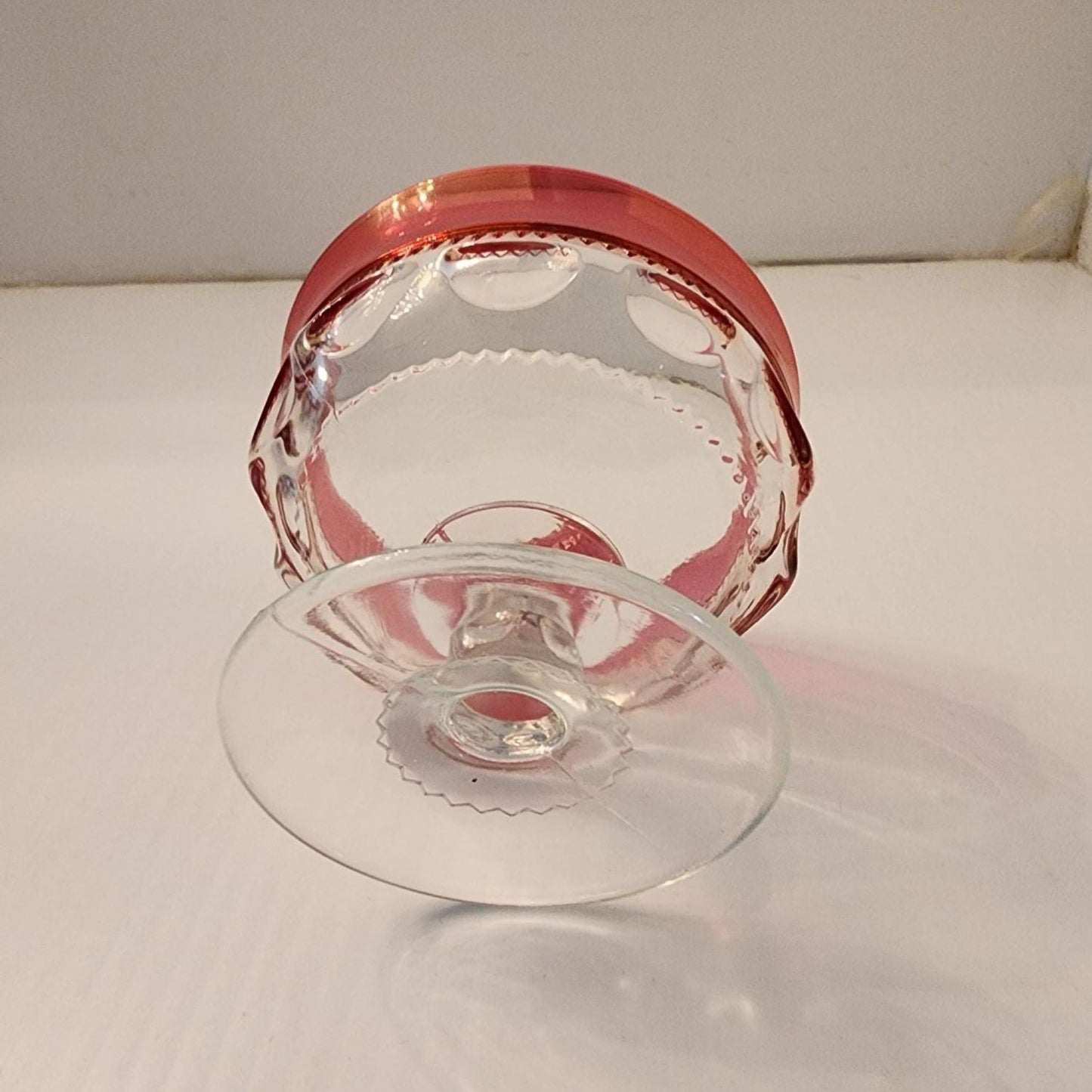 Elegant red glass bowl with a transparent base, ideal for displaying colorful treats.