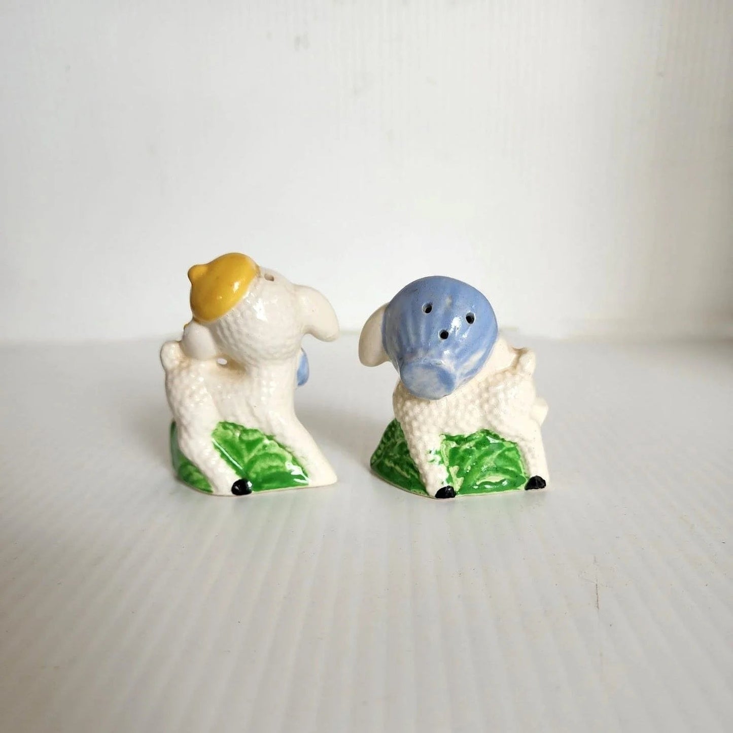 Two sheep figurines with blue bows on their heads.