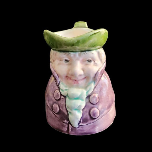 A small porcelain figurine wearing a green hat and a purple coat, showcasing intricate craftsmanship.
