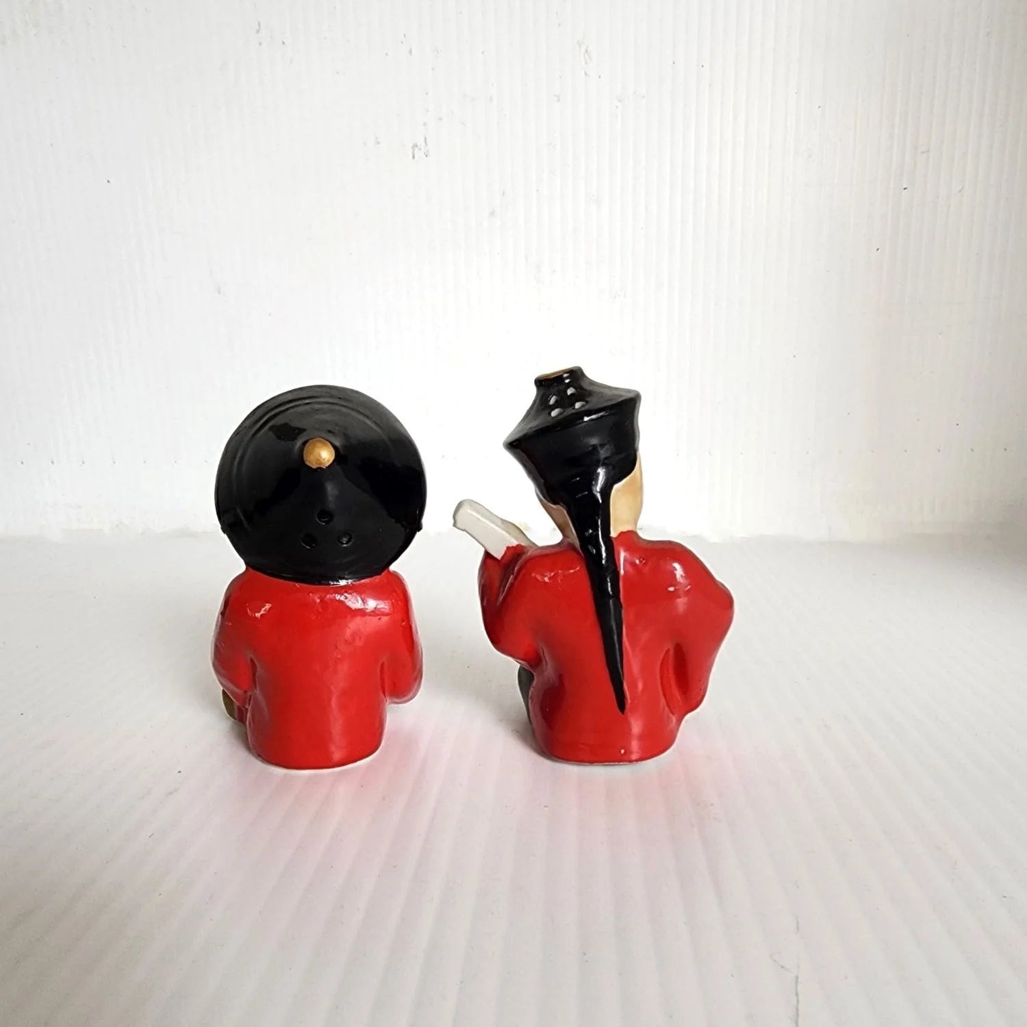 Two Asian figurines sitting on a table, showcasing cultural diversity and artistic craftsmanship.