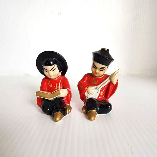 Two Asian figurines sitting on a table, showcasing cultural diversity and artistic craftsmanship.