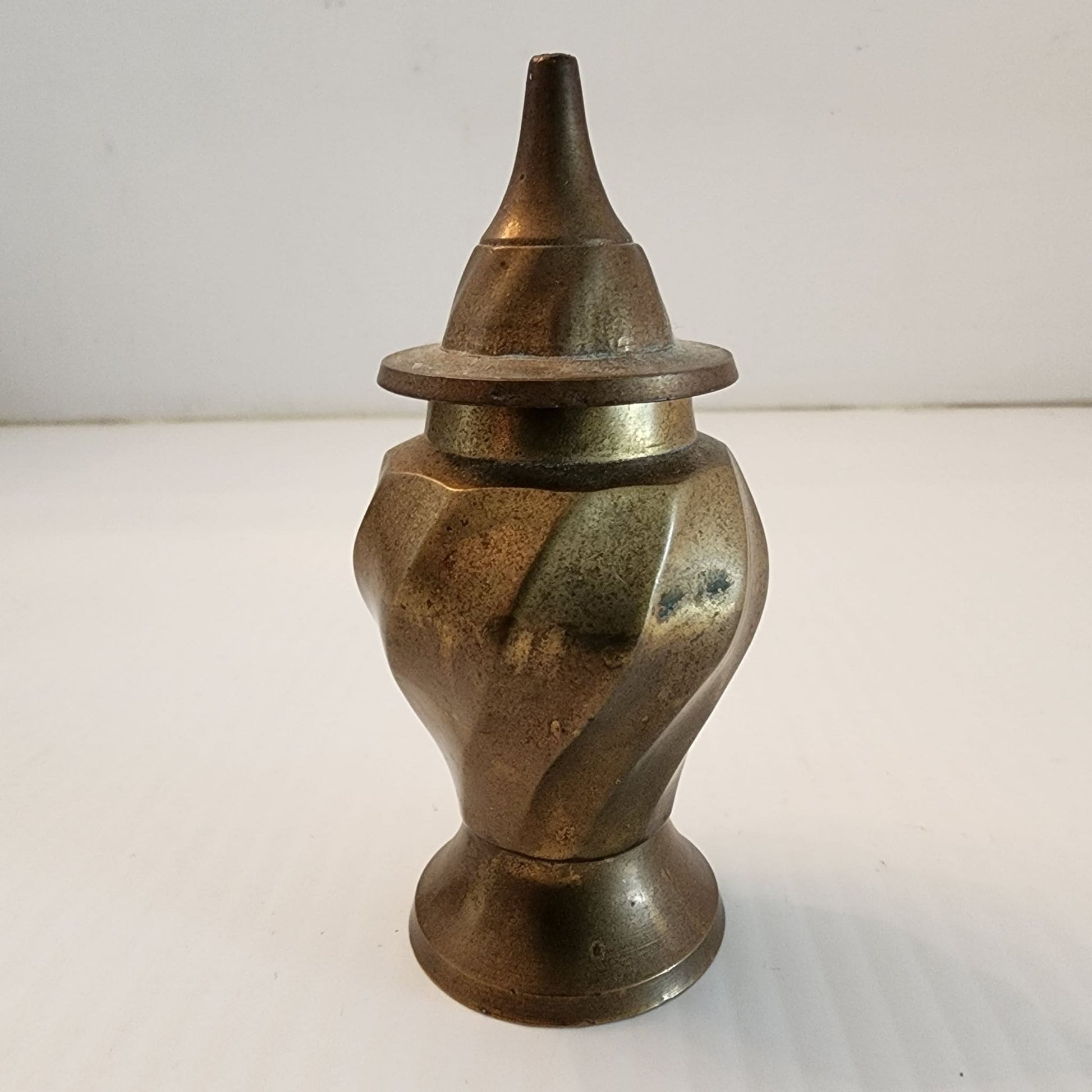A brass vase with a small lid on top, adding elegance and charm to any space.