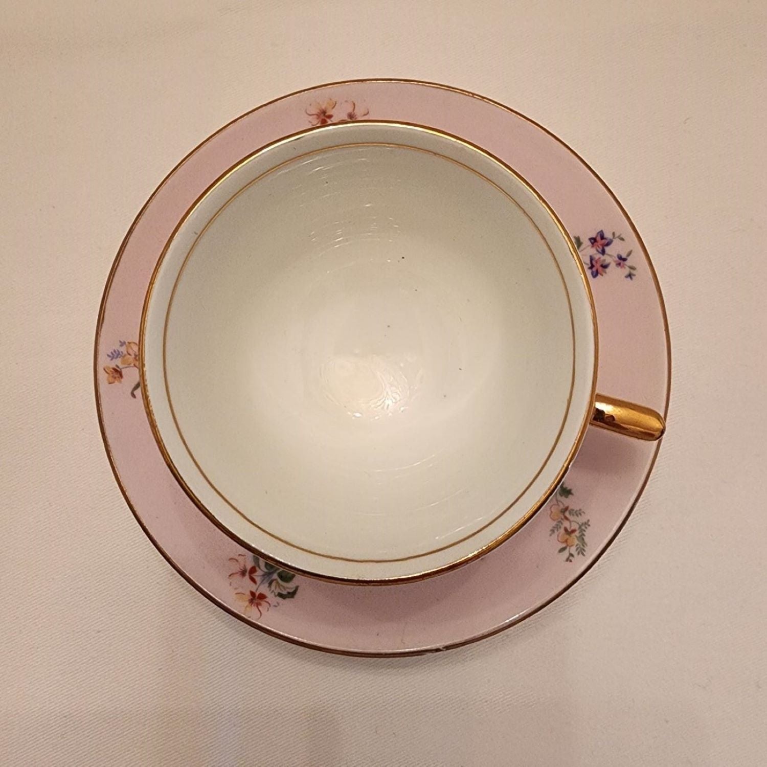 A pinkish teacup and saucer with delicate floral patterns.