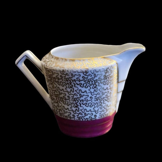 White and pink creamer with elegant gold trim, perfect for serving coffee or tea.
