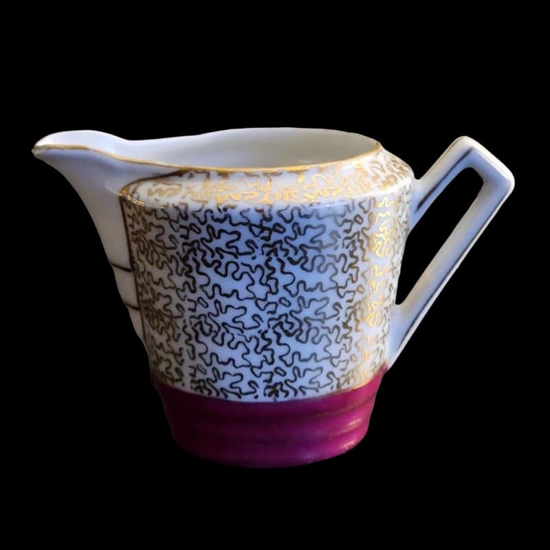White and pink creamer with elegant gold trim, perfect for serving coffee or tea.